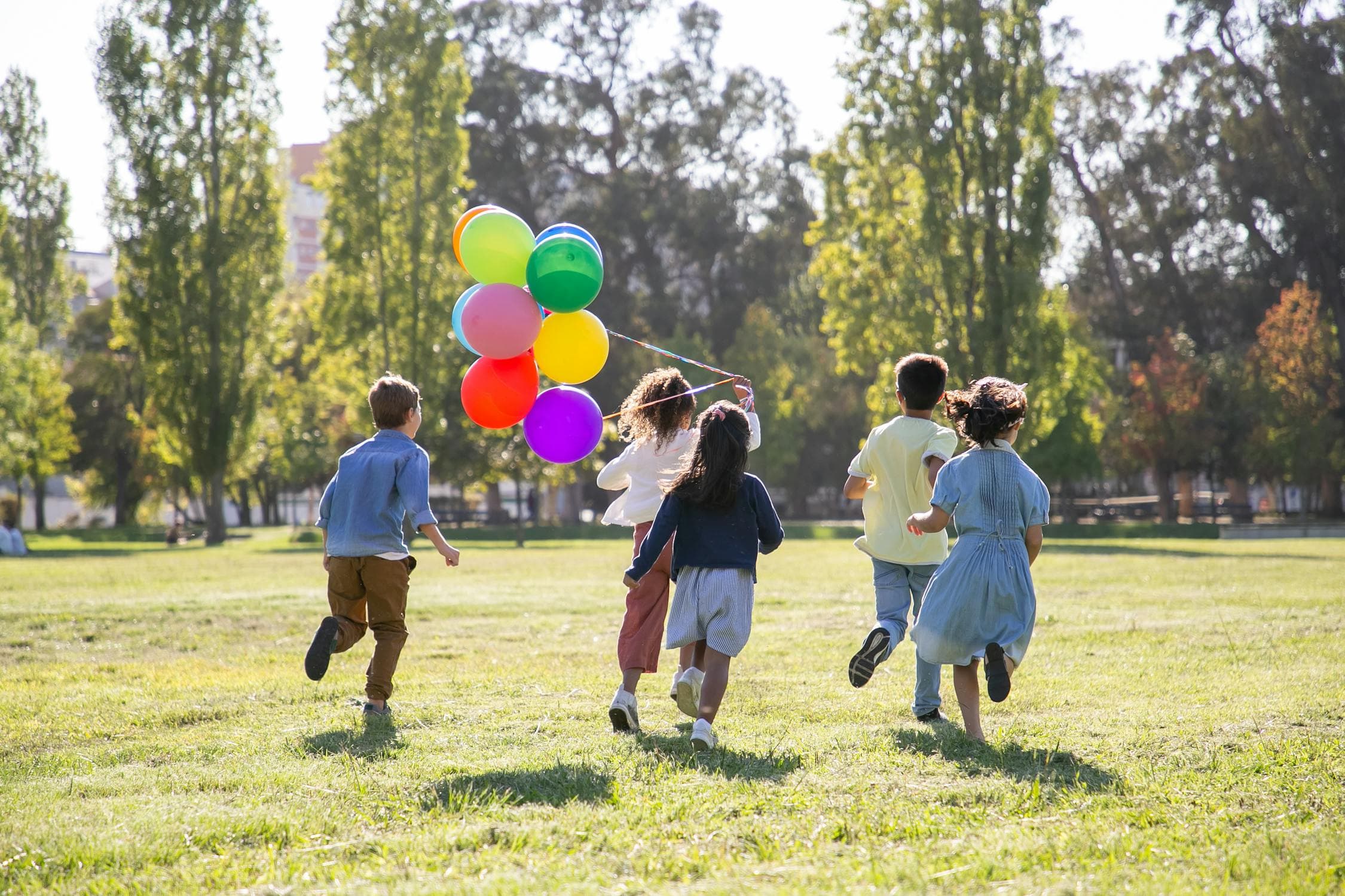 Children playing with balloons on a green grass field outdoors