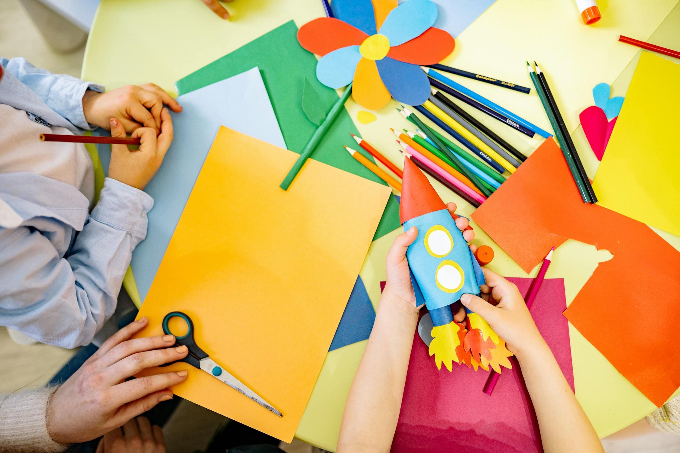 Children doing arts and crafts activities together at a table in a school classroom